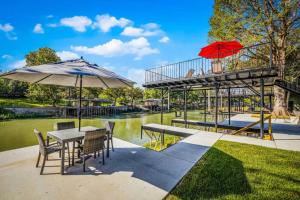 a table and chairs with umbrellas next to a river at Waterfront Dock Fire Pit Book for Wurstfest Family in McQueeney +29 photos
