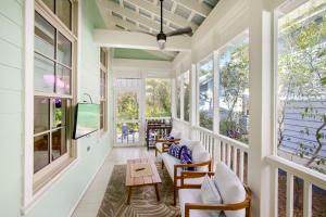un porche grillagé avec des chaises, une télévision et des fenêtres dans l'établissement Barefoot Bungalow by Stay on 30a, à Seagrove Beach