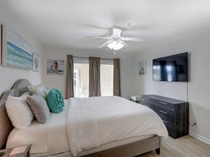 a bedroom with a bed with a ceiling fan and a television at Sweet Location with Sophistication in Tybee Island