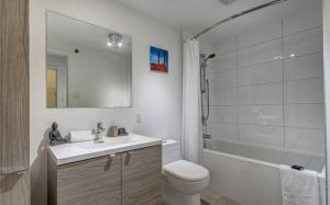 une salle de bain avec un lavabo, des toilettes et un miroir dans l'établissement Corporate Stays Le Shaughn 2 Bedroom, à Montréal