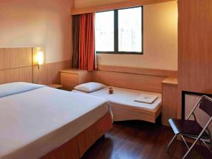 a hotel room with two beds and a window at ibis Curitiba Shopping in Curitiba