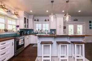 a kitchen with white cabinets and bar stools at A Pura Vida in Edisto Island