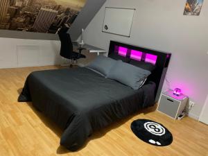a bedroom with a bed with a black comforter and purple lights at Quite House in Villiers-le-Morhier