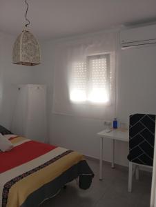 a white bedroom with a bed and a window at Habitación en casa compartida "Al-Mariya" in Almería