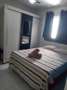 ein Bett mit einem roten ausgestopften Tier, das darauf sitzt in der Unterkunft Condomínio Bezerra in Maragogi