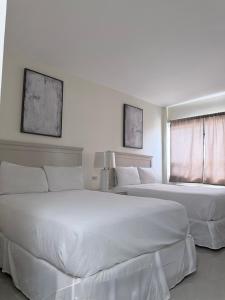 two white beds in a bedroom with two windows at Hotel La Mansión 