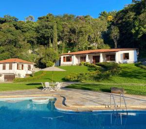 a house with a swimming pool in front of a house at Casa Vale da Serra - Petrópolis in Petrópolis
