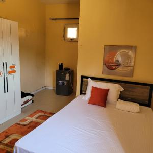 een slaapkamer met een bed met witte lakens en rode kussens bij Ganou Mboro in Mboro