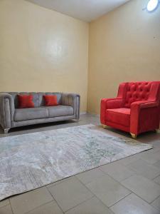 een woonkamer met een bank en een rode stoel bij Ganou Mboro in Mboro
