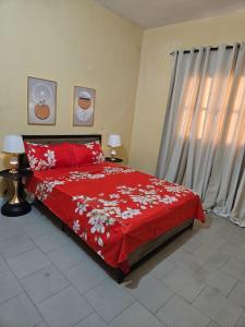 een slaapkamer met een bed met een rood dekbed bij Ganou Mboro in Mboro