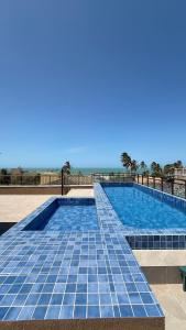 Una piscina con suelo de baldosas azules y el océano. en Canoas Flecheiras - Ap 104, en Trairi