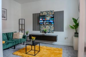 een woonkamer met een groene bank en een tv bij Stylish 3-Bed 15min to Manchester City Centre in Ashton under Lyne