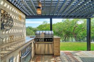 an outdoor kitchen with a grill under a pergola at Waterfront Sleeps 16 Perfect for Family & Wurstfest in McQueeney
