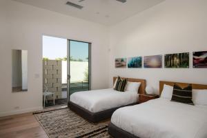 two beds in a room with white walls and windows at Krypton @ Elemento49 Pool Spa Sleeps 16 in Desert Groves Mobile Home Park +38 photos