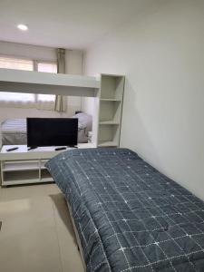 a bedroom with a bed and a desk with a laptop at Monoambiente cómodo 4 pax in Necochea