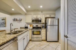 kuchnia z białymi szafkami i urządzeniami ze stali nierdzewnej w obiekcie HP 12W Gulf Front Condo by 30A Escapes w mieście Rosemary Beach