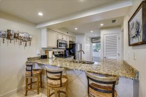 kuchnia z granitowym blatem i stołkami w obiekcie HP 12W Gulf Front Condo by 30A Escapes w mieście Rosemary Beach