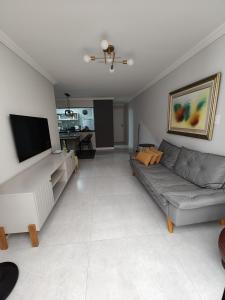 ein Wohnzimmer mit Couch und Flachbildfernseher in der Unterkunft Apartamento de 3 qts com garagem a 50 metros orla da Praia do Morro in Guarapari