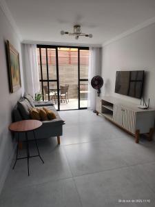 a living room with a couch and a television at Excelente apartamento com vaga garagem a 50 metros da orla da Praia do Morro Guarapari in Guarapari