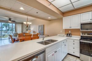 HP 124 Condo by 30A Escapes في روزماري بيتش: مطبخ مع دواليب بيضاء وغرفة طعام