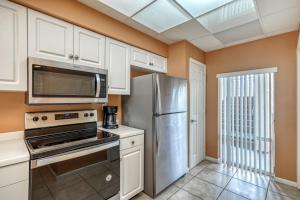 HP 124 Condo by 30A Escapes في روزماري بيتش: مطبخ بخزائن بيضاء وثلاجة من الفولاذ المقاوم للصدأ