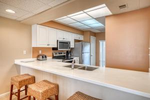 HP 124 Condo by 30A Escapes في روزماري بيتش: مطبخ مع دواليب بيضاء وكاونتر مع الكراسي +20 صورة