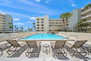 a swimming pool with lounge chairs and a table and a building at Gulf and Bay Club- F401 in Siesta Key