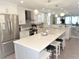 a large white kitchen with a large island with bar stools at Gulf and Bay Club- F401 in Siesta Key