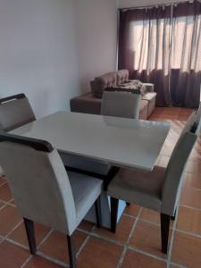 einem Esstisch mit 2 Stühlen und einem Sofa in der Unterkunft Apartamento temporada Guarujá in Guarujá
