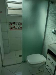 ein Badezimmer mit weißer Toilette und Dusche in der Unterkunft Apartamento temporada Guarujá in Guarujá