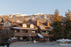 um grande edifício com uma montanha coberta de neve ao fundo em Whistler Village Retreat, Private Hot Tub & Sauna em Whistler