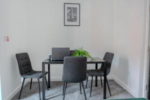 een eettafel met stoelen en een laptop erop bij Stylish 3-Bed 15min to Manchester City Centre in Ashton under Lyne