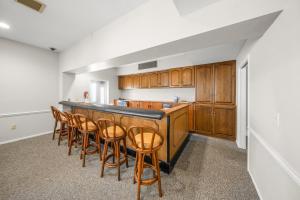 a kitchen with wooden cabinets and a bar with stools at Gulf and Bay Club- F105 in Siesta Key
