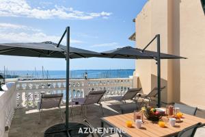 a patio with a table and umbrellas on a balcony at Azurenting - vue sur le port - roof top 3 in Vallauris +13 photos