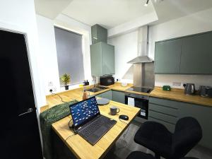 een laptop op een houten tafel in een keuken bij Stylish 3-Bed 15min to Manchester City Centre in Ashton under Lyne