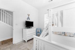 Ein weißes Schlafzimmer mit einem Fernseher auf einer Kommode und einer Treppe in der Unterkunft Hidden Gem #6 by 30A Escapes in Seacrest + 21 Fotos