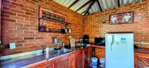 uma cozinha com parede de tijolos, pia e geladeira em Pousada dos Chalés - Araras em Araras Petropolis mais 58 fotografias