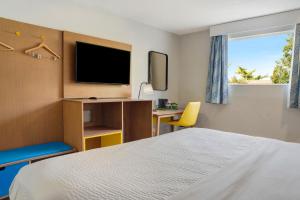 a hotel room with a bed and a desk and a television at Days Inn by Wyndham Omaha - West Dodge in Omaha