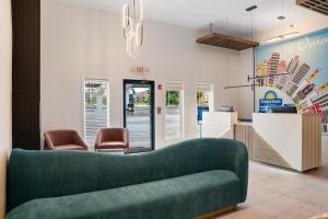 a lobby with a green couch and two chairs at Days Inn by Wyndham Omaha - West Dodge in Omaha
