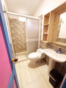 a bathroom with a toilet and a sink at Hotel Jardín Del Río in El Bosque