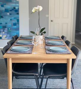 une table avec des assiettes et des verres et une fleur dessus dans l'établissement Modern townhouse, walking distance to town centre, à Yarra Glen