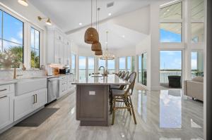 a kitchen with white cabinets and a table with chairs at Lemon Bay Luxe – Dock, Beach & Manasota Vibes in Punta Gorda Beach