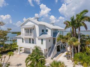 a white house on the beach with palm trees at Lemon Bay Luxe – Dock, Beach & Manasota Vibes in Punta Gorda Beach