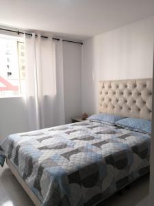 a bedroom with a bed with a quilt and a window at Privado y fascinante Apartaestudio San Alonso in Bucaramanga
