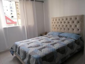 a bedroom with a bed with a quilt and a window at Privado y fascinante Apartaestudio San Alonso in Bucaramanga