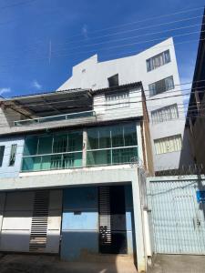 a tall white building with a gate in front of it at Lar Urbano in Manhuaçu