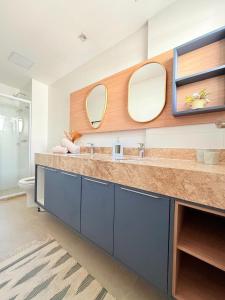 un baño con dos lavabos y dos espejos en Cobertura com Piscina Privativa em Resort Pé na Areia, en Arraial do Cabo