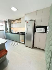 una cocina con nevera y microondas en Cobertura com Piscina Privativa em Resort Pé na Areia, en Arraial do Cabo