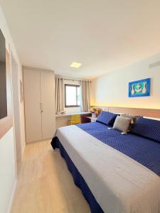 Un dormitorio con una cama grande con sábanas azules. en Cobertura com Piscina Privativa em Resort Pé na Areia, en Arraial do Cabo
