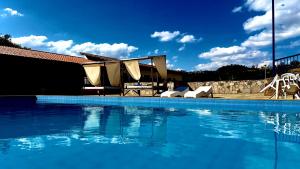 a large swimming pool with chairs and a table at Nova Aliança Suítes por Temporada em Amparo NÃO SOMOS POUSADA in Amparo